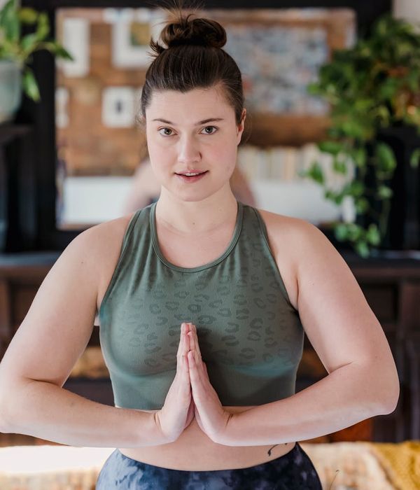Woman holding a serene yoga pose in a dark room with teal light.
